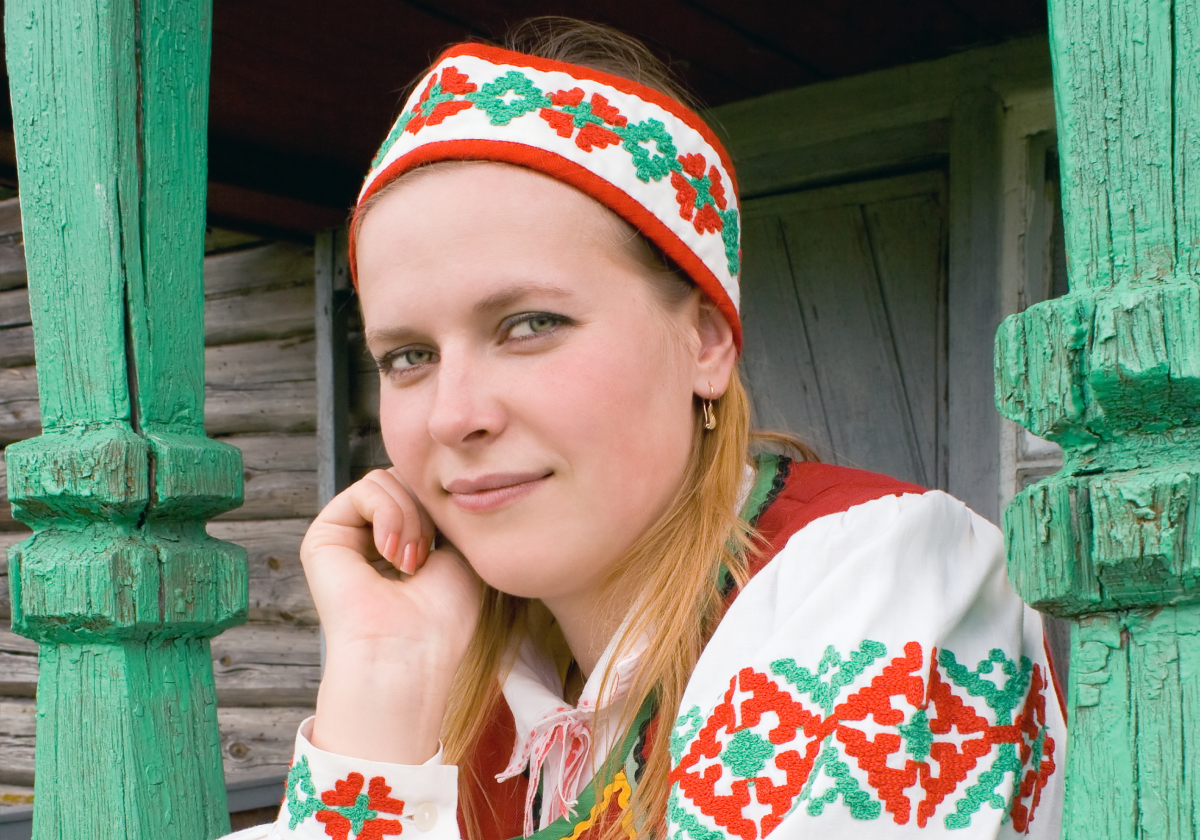 Woman smiling on a porch wearing traditional clothing from Belarus