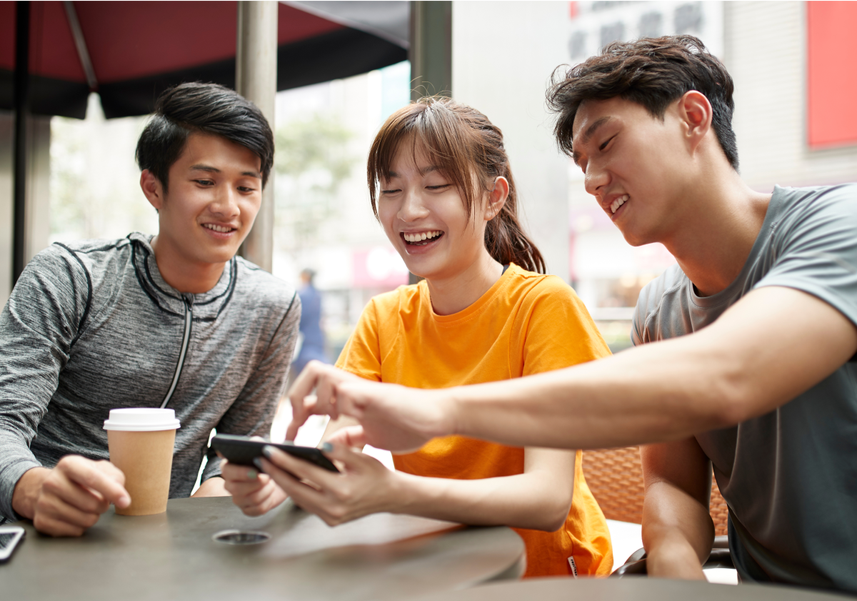 Photo of friends at a table looking at a phone in Taiwan