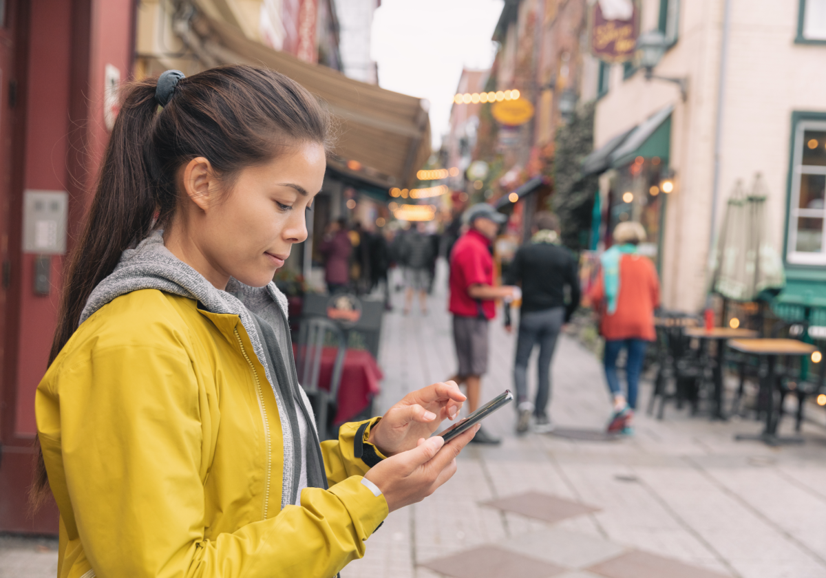 Photo of woman on her phone in a city in Canada